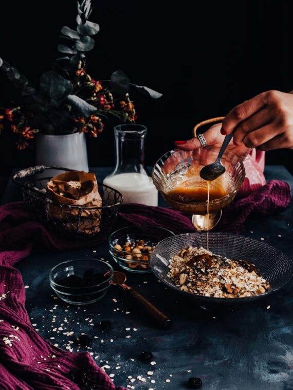 Woman hands drizzling honey on a granola bowl